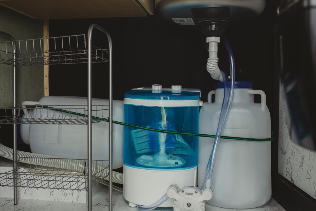 Organized under kitchen sink with storage bins and cleaning supplies