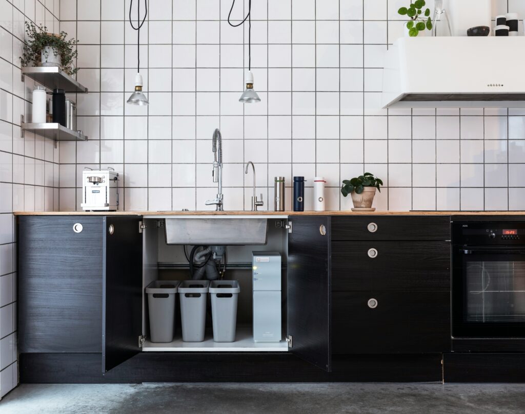 Under kitchen sink organized with dedicated storage zones and pull-out bins