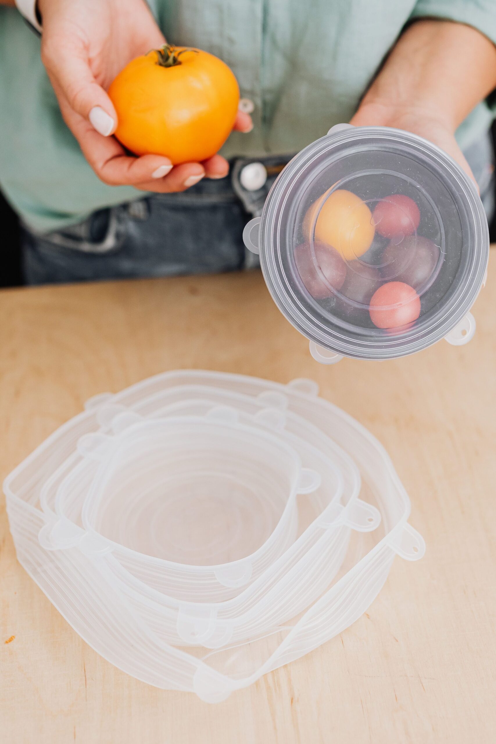 Reusable silicone food covers in different sizes used to store fresh fruit on a kitchen table.