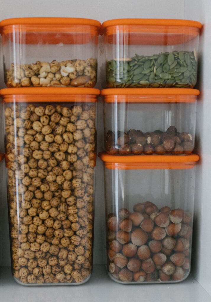Stackable clear storage containers filled with nuts and seeds in a pantry