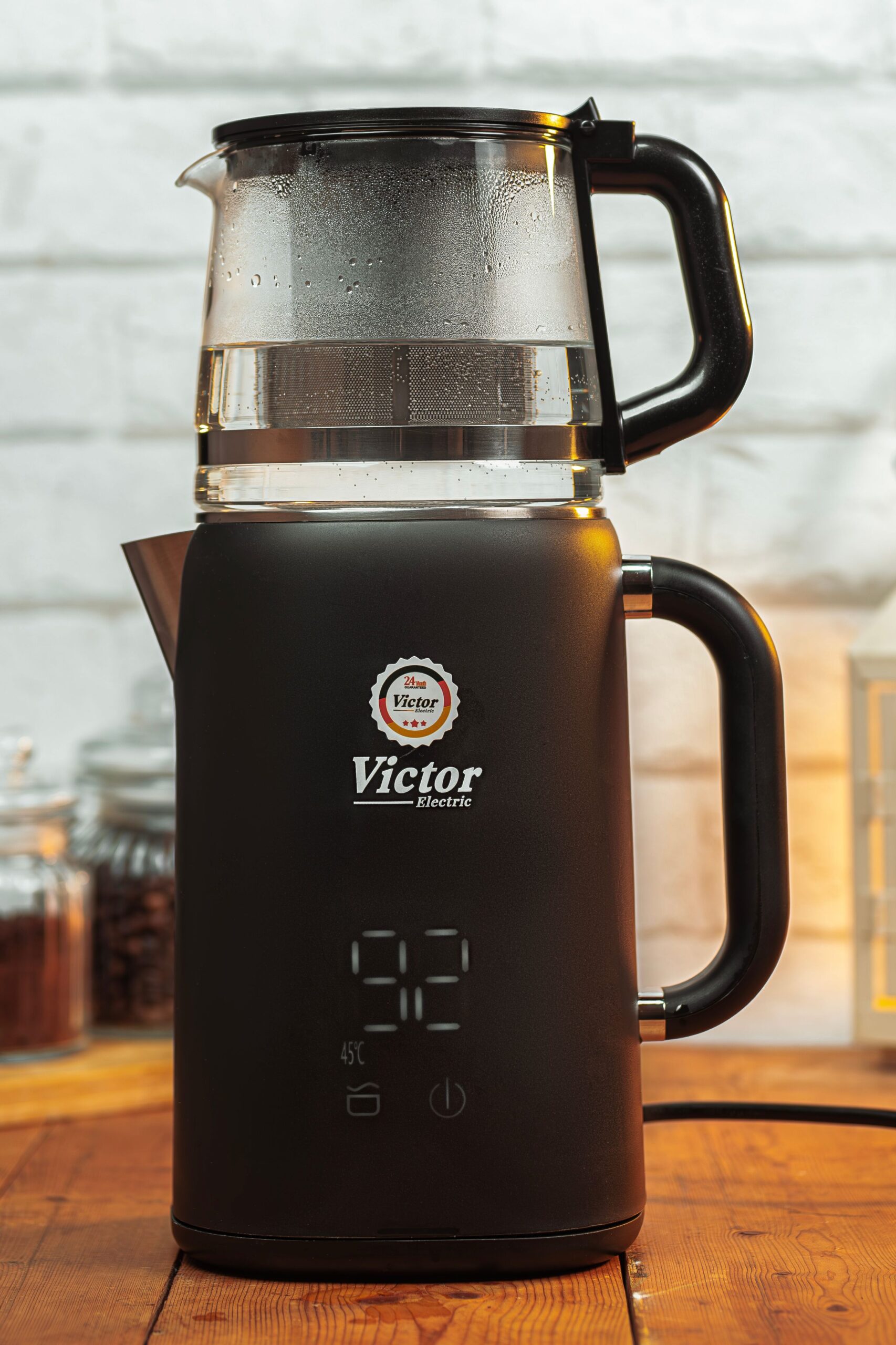 Electric tea kettle with glass tea infuser and temperature control on a wooden kitchen countertop